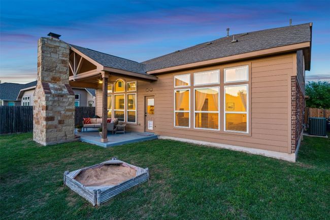 Back of property at dusk with a fenced backyard, a patio, outdoor lounge area, roof with shingles, and a chimney | Image 32