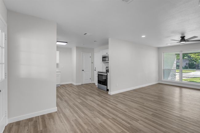 Unfurnished living room featuring light wood-style floors, baseboards, ceiling fan, and recessed lighting | Image 6