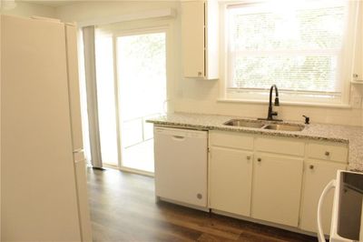 Kitchen with dark wood-type flooring, white appliances, plenty of natural light, and sink | Image 3