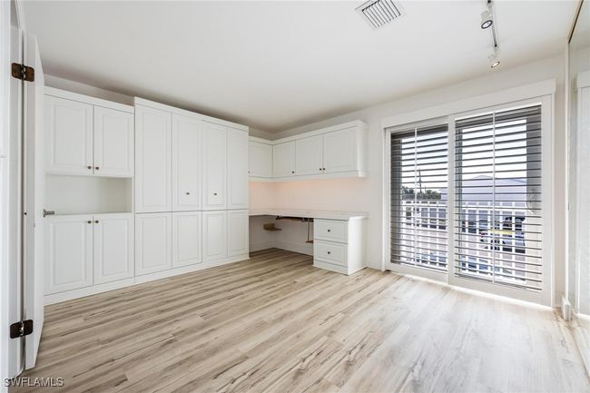 Bedroom with built in desk and cabinets, that can be used as an office, featuring a murphy bed and a small balcony. | Image 27