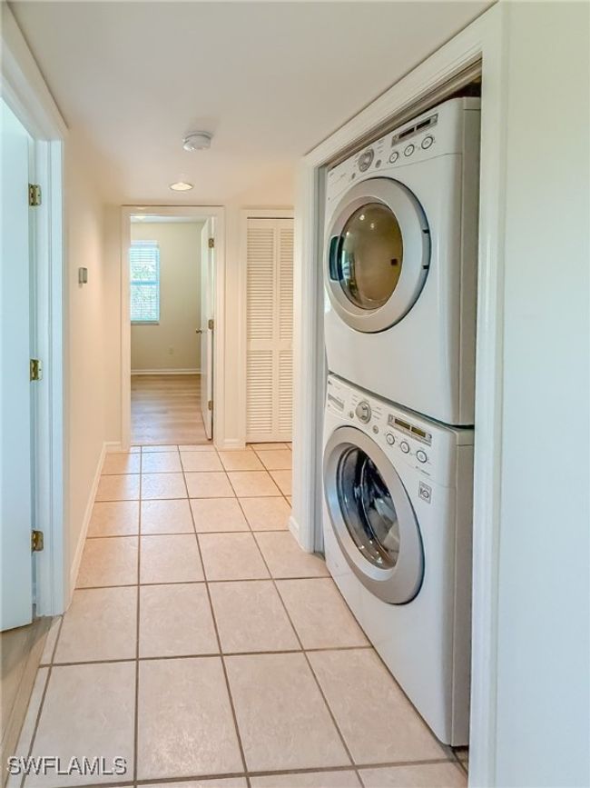 Laundry area featuring light tile patterned floors, baseboards, laundry area, and stacked washer and clothes dryer | Image 30