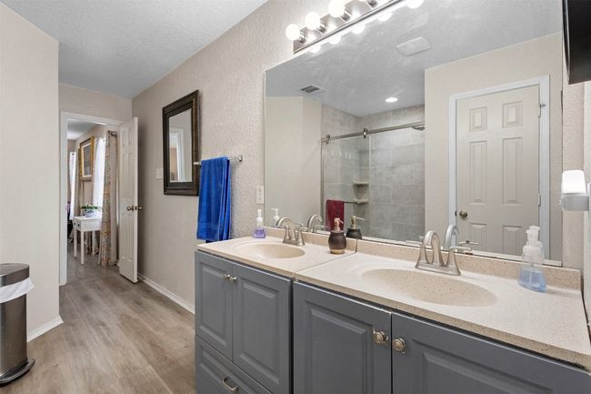 Bathroom featuring wood finished floors, a sink, tiled shower, and a textured ceiling | Image 27
