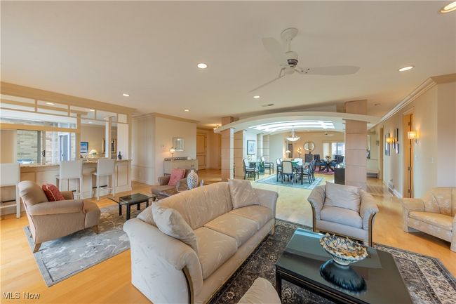 Living room with light wood-style floors, crown molding, and arched walkways | Image 15