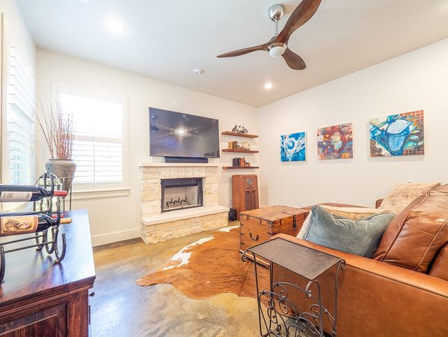 Living area with finished concrete floors, a fireplace, ceiling fan, and recessed lighting | Image 11