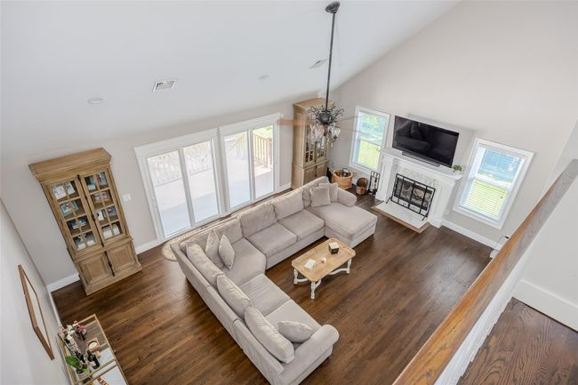Living room featuring a premium fireplace, wood finished floors, and high vaulted ceiling | Image 21