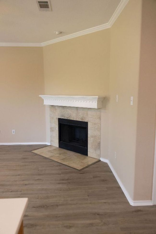 Detailed view of a fireplace, ornamental molding, baseboards, and new laminate floors | Image 9