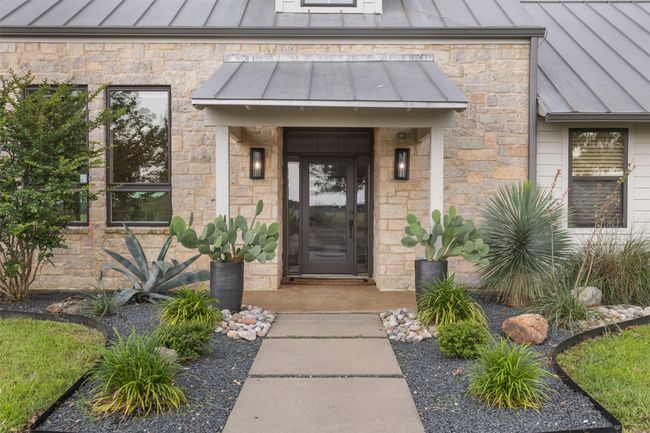 Property entrance with a standing seam roof, a metal roof, and stone siding | Image 9