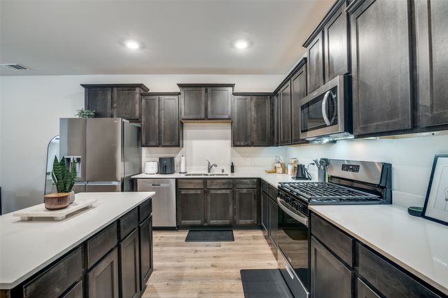 Kitchen featuring appliances with stainless steel finishes, light wood-style floors, light countertops, recessed lighting, and dark brown cabinetry | Image 13