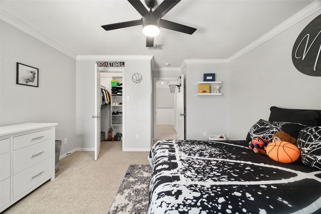 Bedroom featuring visible vents, a closet, ornamental molding, a walk in closet, and light carpet | Image 23