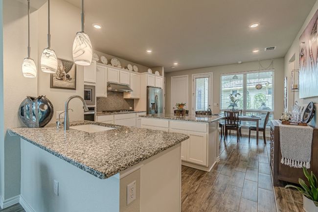 Kitchen featuring under cabinet range hood, appliances with stainless steel finishes, a center island, a peninsula, and tasteful backsplash | Image 11