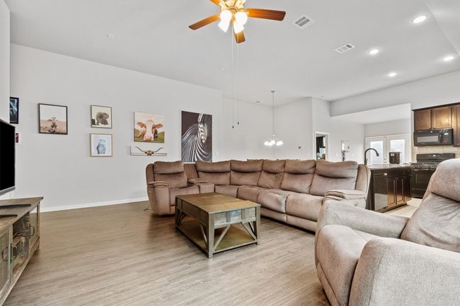 Living area with a ceiling fan, wood-style flooring, a chandelier, and recessed lighting. | Image 12