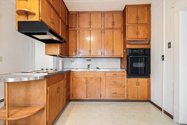Kitchen with black oven, white gas stovetop, and sink | Image 11