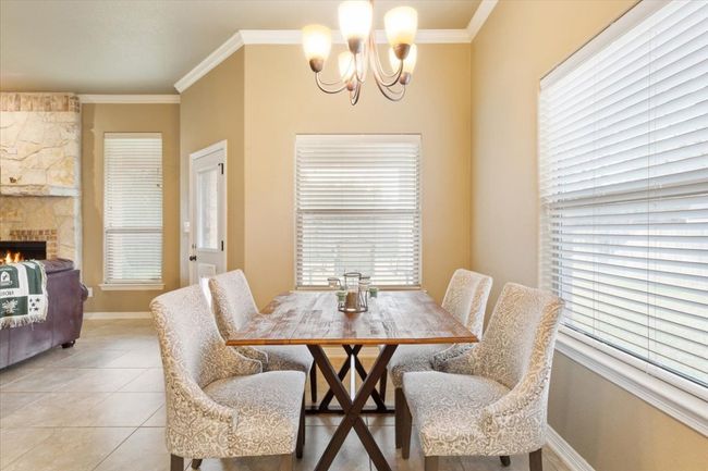 Dining room featuring baseboards, ornamental molding, light tile patterned floors, a fireplace, and a notable chandelier | Image 14