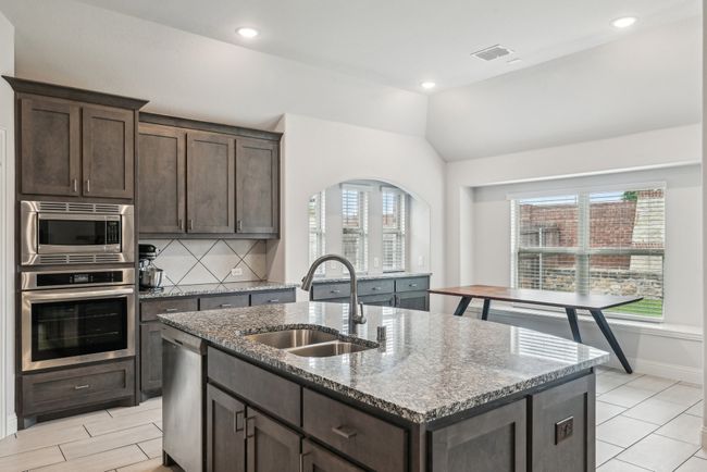 Kitchen with stainless steel appliances, a sink, healthy amount of natural light, dark brown cabinets, and lofted ceiling | Image 19