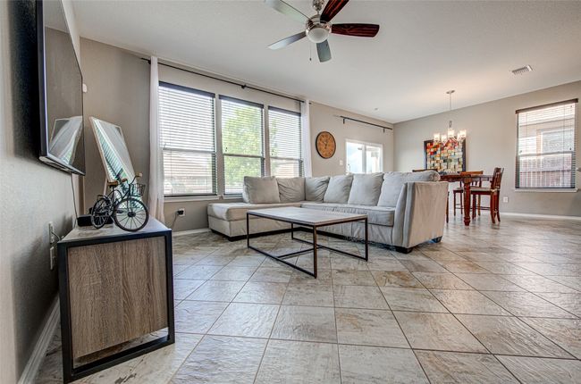 Living room with visible vents, baseboards, and ceiling fan with notable chandelier | Image 6