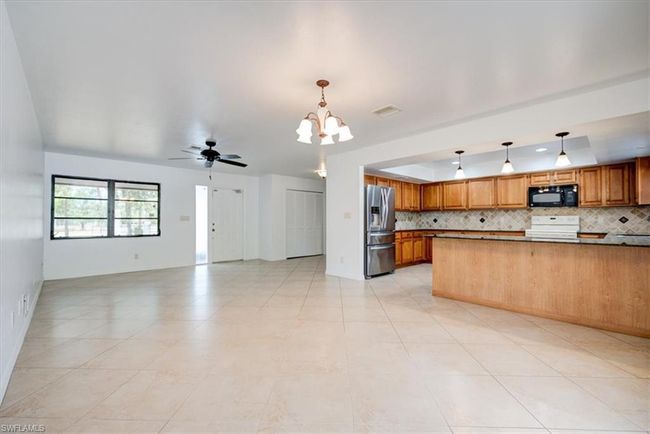 Kitchen with tasteful backsplash, range, black microwave, open floor plan, and stainless steel fridge | Image 9