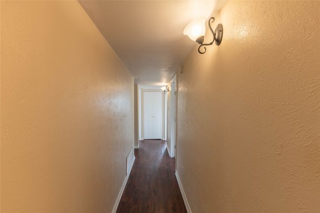 Hall with dark wood-style flooring, baseboards, and a textured wall | Image 17
