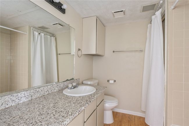 Full bathroom granite counter-top vanity, wood finished floors, and curtained shower | Image 6