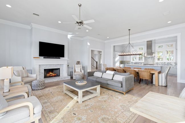 Living area featuring stairs, crown molding, a premium fireplace, visible vents, and light wood-style floors | Image 7