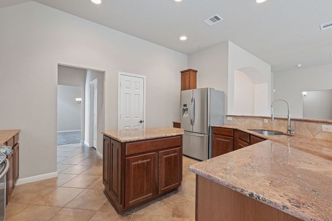 Kitchen featuring stainless steel appliances, granite counters, vaulted ceiling, backsplash, and tile flooring | Image 5