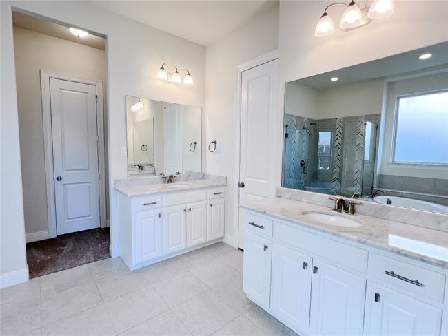 Full bathroom with a shower stall, two vanities, tile patterned floors, and a tub to relax in | Image 23