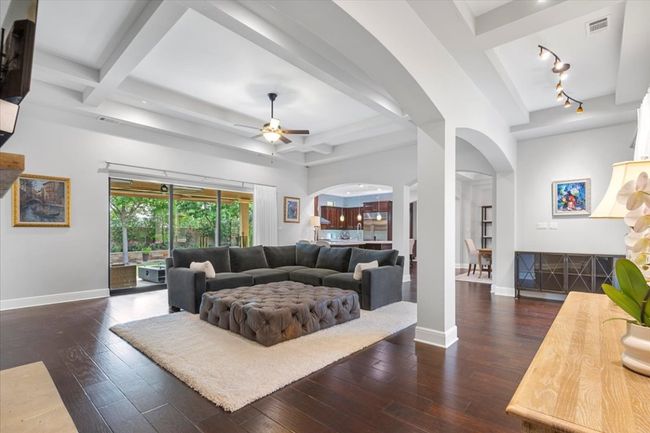 Living room with beam ceiling, arched walkways, baseboards, ceiling fan, and dark wood-type flooring | Image 8