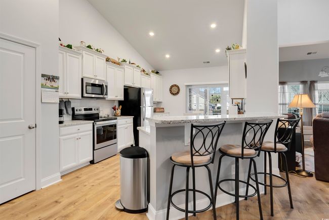 Kitchen with appliances with stainless steel finishes, a breakfast bar, light stone counters, and kitchen peninsula | Image 7