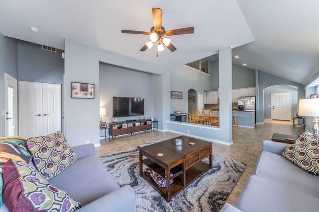 Living room with arched walkways, ceiling fan, high vaulted ceiling, light tile patterned flooring, and baseboards | Image 5