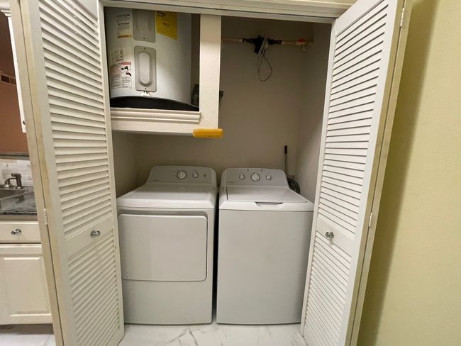 Laundry room with water heater, light marble finish flooring, and washer and clothes dryer | Image 8