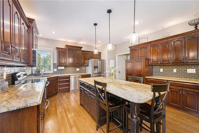 Kitchen with stainless steel appliances, backsplash, a sink, light wood finished floors, and light stone counters | Image 16