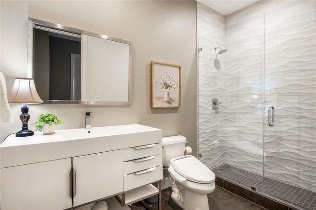 En suite bathroom in the secondary bedroom has a large vanity, lots of storage and a beautiful large walk-in shower. | Image 26