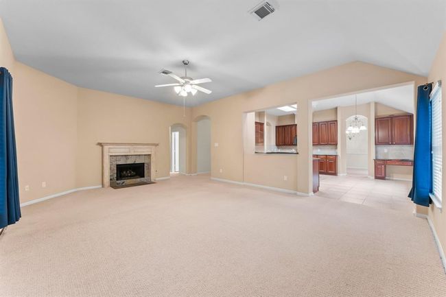 The spacious family room is filled with natural light from a wall of windows and showcases a cozy gas fireplace and high vaulted ceilings. Open to the kitchen and breakfast area, this inviting space is ideal for everyday living and effortless entertaining. | Image 17