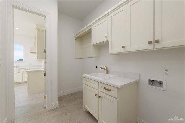 Dedicated Laundry Room for ApartmentConvenient in-unit laundry room with custom cabinetry, hanging rod, and tankless water heater—ideal for long-term comfort and ease.Bright laundry room with built-in upper cabinets, utility sink, quartz counters, and space for full-size washer/dryer setup. | Image 33