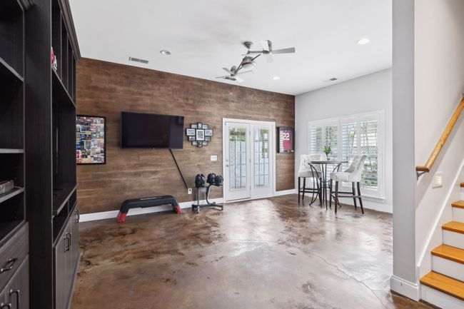 Lower level rec room with wood accent wall, concrete floors, and walk-out access. | Image 35