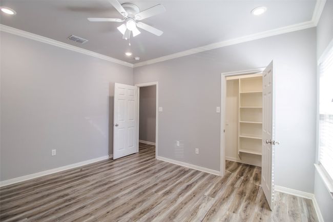 Unfurnished bedroom featuring crown molding, a spacious closet, light wood-style floors, recessed lighting, and a ceiling fan | Image 12