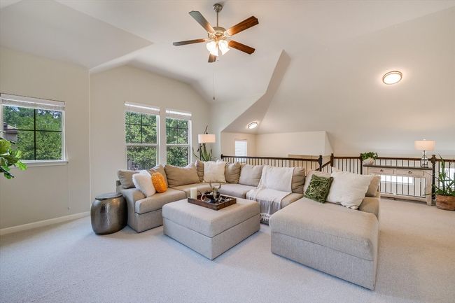 Carpeted living area featuring a ceiling fan, vaulted ceiling, and baseboards | Image 20