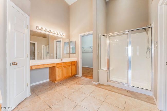 Full bath featuring a stall shower, vanity, tile patterned flooring, baseboards, and a high ceiling | Image 29
