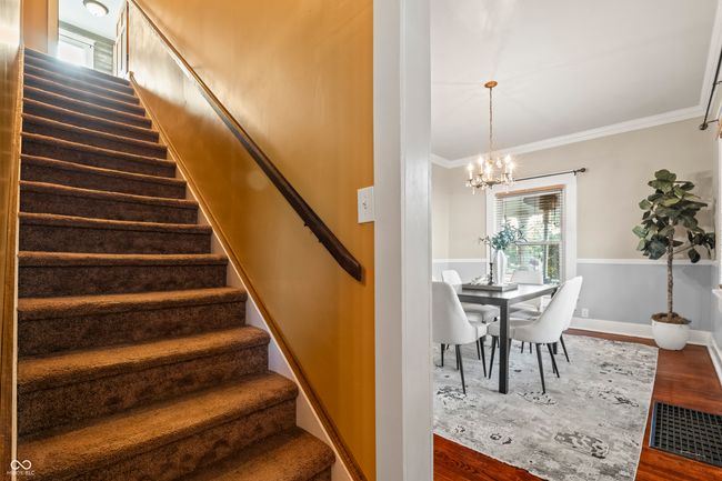 staircase with wood finished floors, crown molding, and a chandelier | Image 29