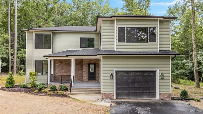 View of front of property featuring a porch, an attached garage, driveway, and stone siding | Image 7