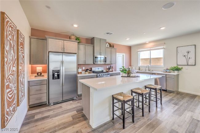 Kitchen with appliances with stainless steel finishes, light wood-style. Photo is representational only; actual home finishes may vary flooring, a breakfast bar, light countertops, and recessed lighting | Image 14