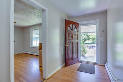 Foyer featuring a textured ceiling, baseboard heating, and light hardwood / wood-style floors | Image 3