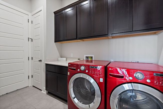 The laundry is downstairs and features washer and dryer and cabinets. | Image 24