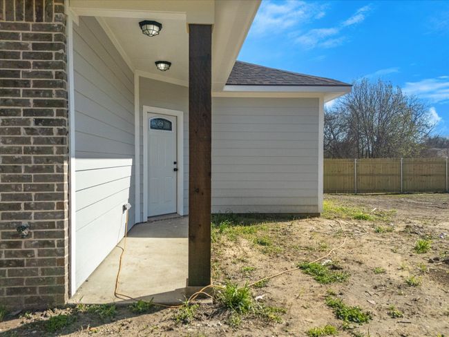 Entrance to property with brick siding, a shingled roof, and fence | Image 32