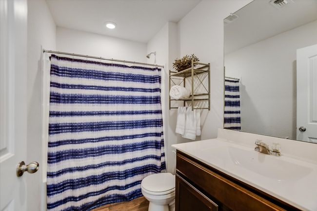 Full bathroom featuring vanity, a shower with curtain, toilet, and visible vents | Image 15