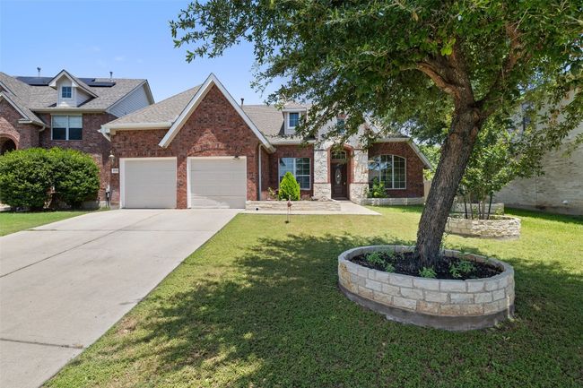 Traditional home featuring a garage, a front yard, concrete driveway, a shingled roof, and brick siding | Image 4