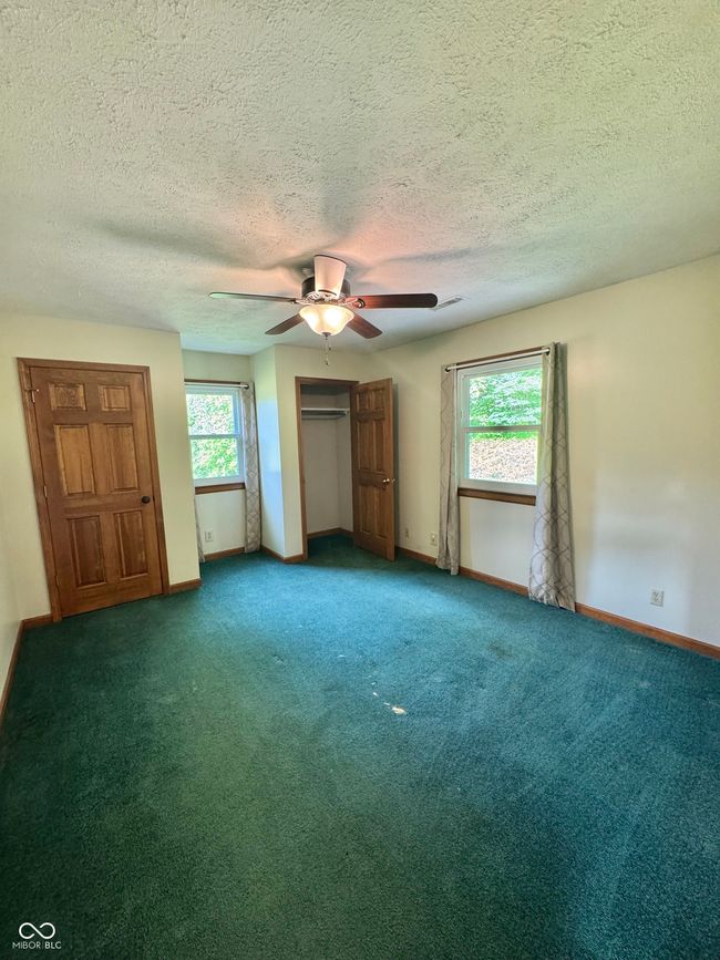 unfurnished bedroom featuring baseboards, carpet floors, a textured ceiling, and a ceiling fan | Image 54