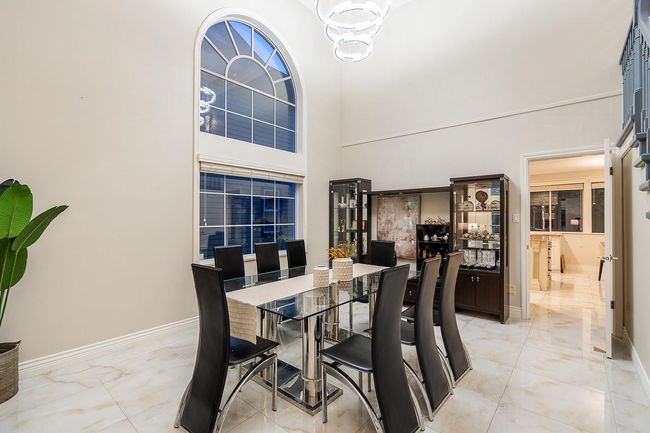 Dining space with baseboards, light marble finish flooring, a chandelier, and a high ceiling | Image 7