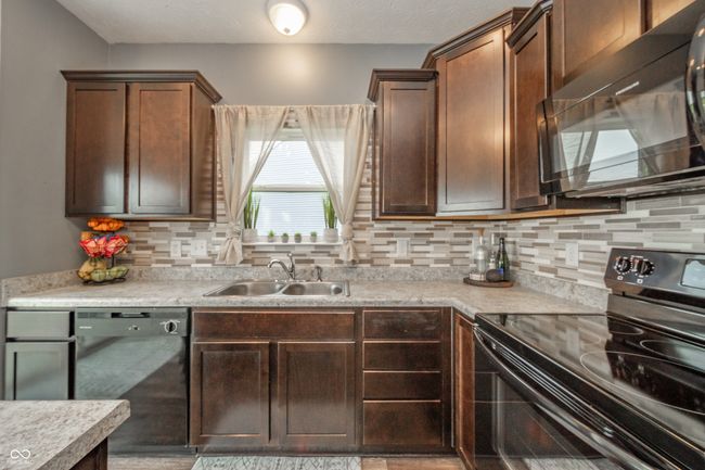 kitchen featuring black appliances, a sink, decorative backsplash, and light countertops | Image 19