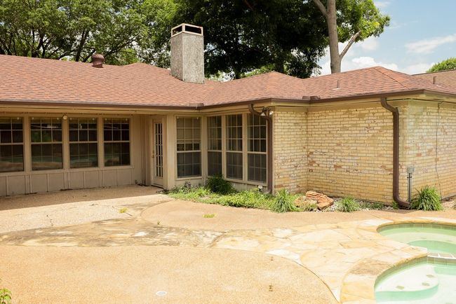 Back of house with a chimney, an in-ground hot tub, brick siding, and a shingled roof | Image 28
