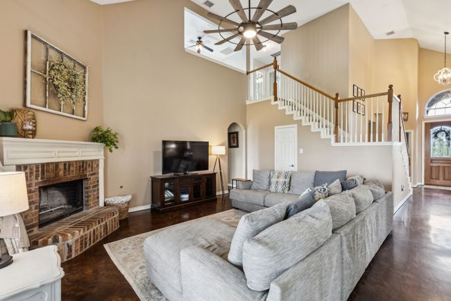 Living area featuring a ceiling fan, high vaulted ceiling, arched walkways, and stairway | Image 8